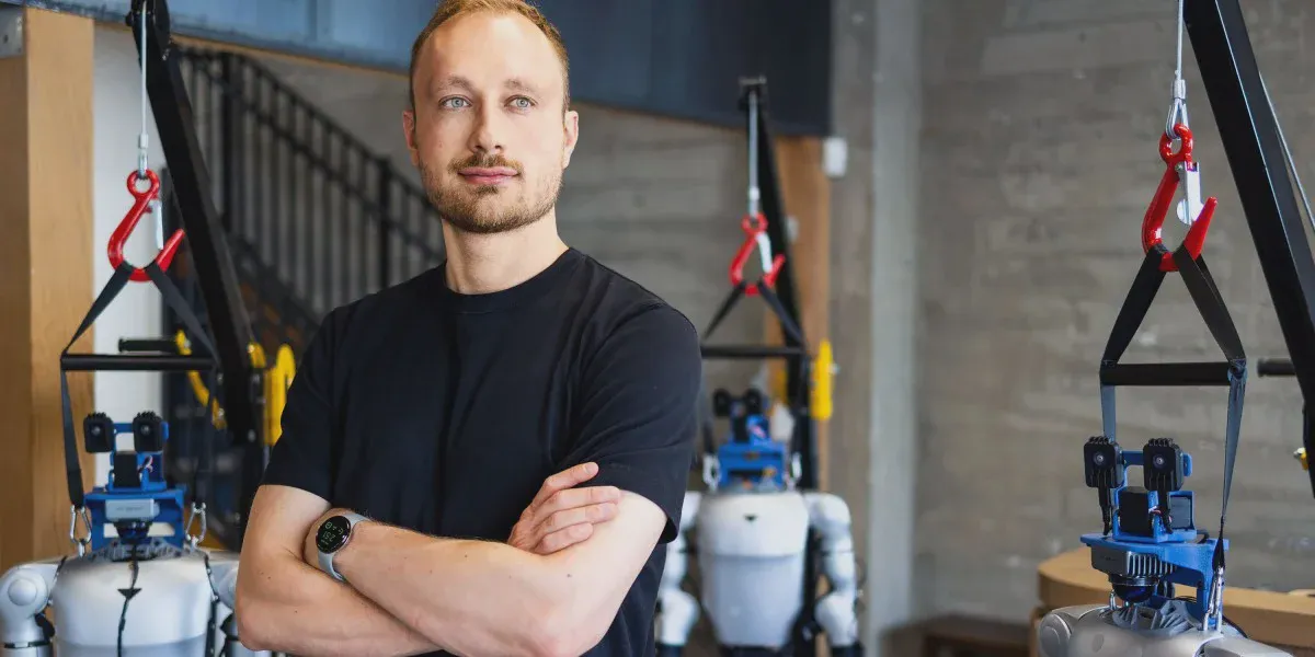 Danijar Hafner đứng giữa những robot hình người trong văn phòng