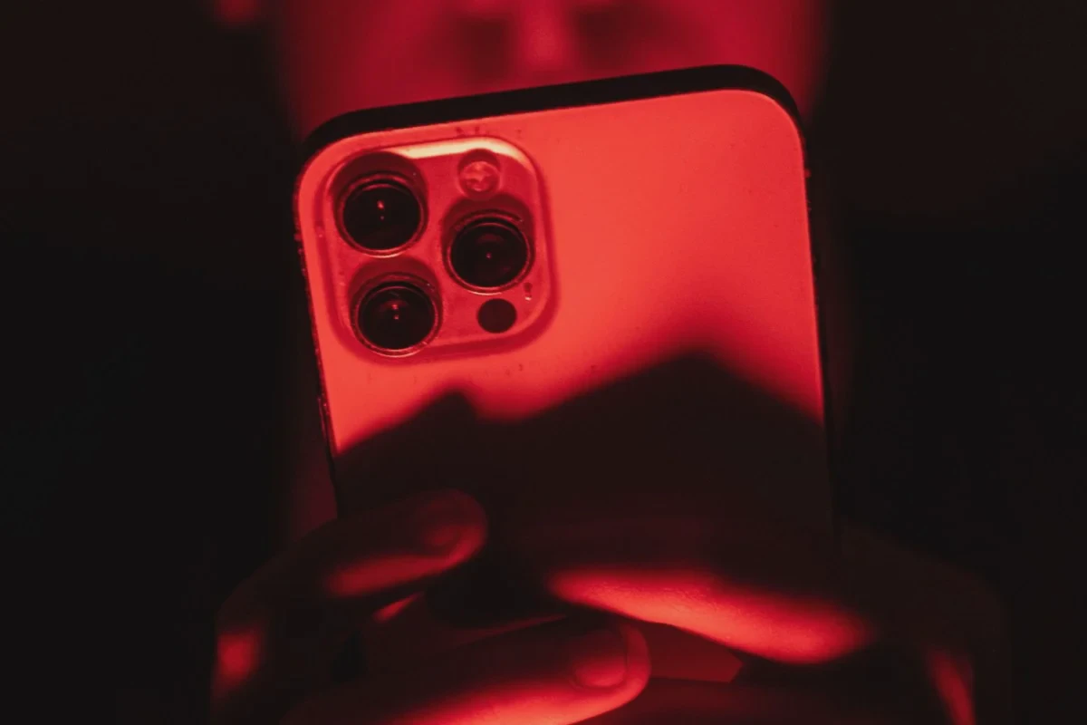 Một người cầm iPhone trước phông nền màu đỏ